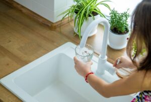 Ragazza beve acqua dal rubinetto